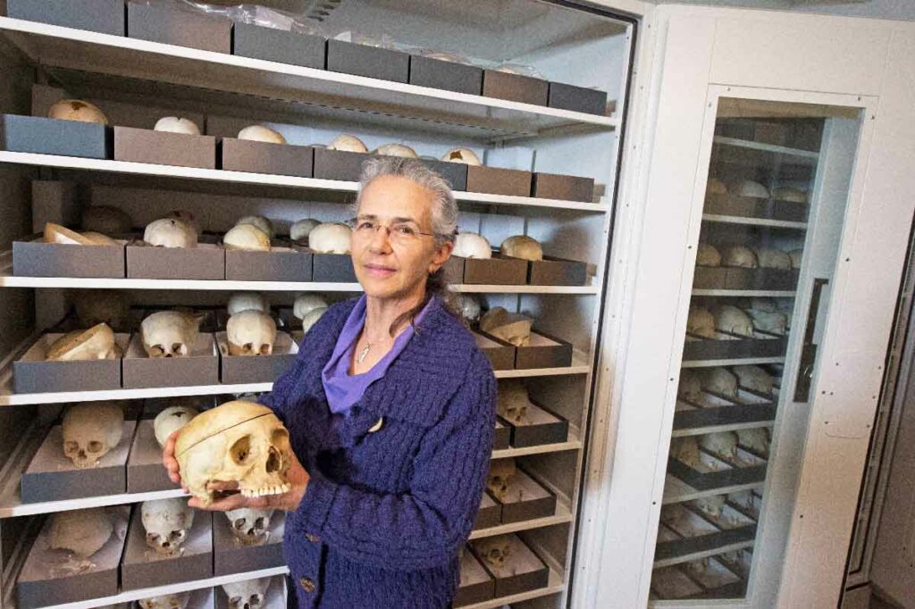 Dorothy Dechant holding a skull while standing in front of the collection