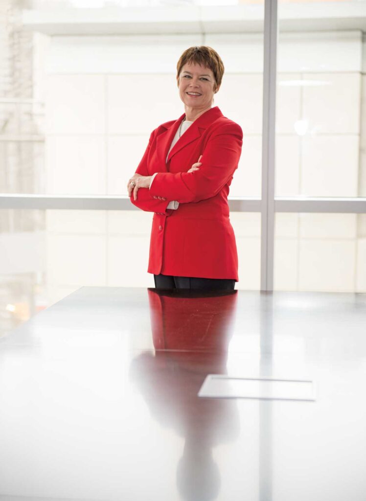 Joanne standing in office in red jacket with arms crossed