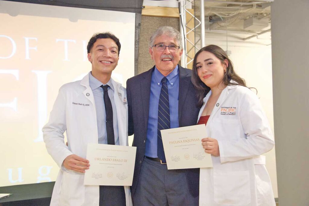 Dr. Lundergan ’81 presents certificates to Drs. Orlando Ebalo III ’25 and Paulina Esquivias ’25 during the senior research poster presentations on April 18, 2025.